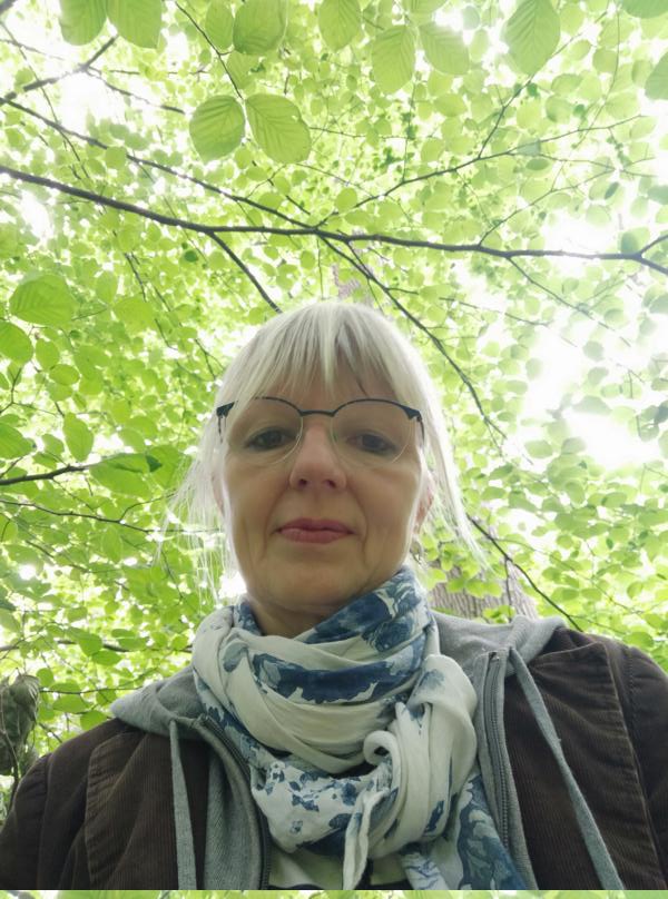 Frau unterm lichten Blätterdach beim Waldbaden