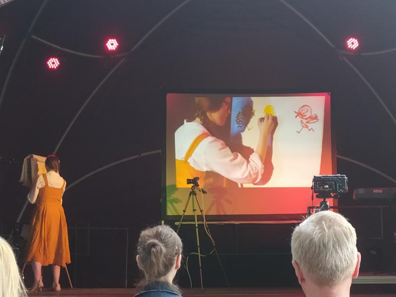 Während eine Frau ein Bild malt, wird dieses simultan auf eine Leinwand übertragen